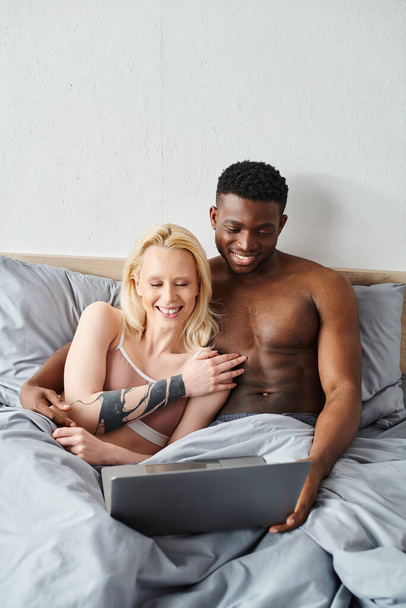 Мультикультурний хлопець і дівчина насолоджуються миттю близькості, зручно лежачи в ліжку разом. - Фото, зображення