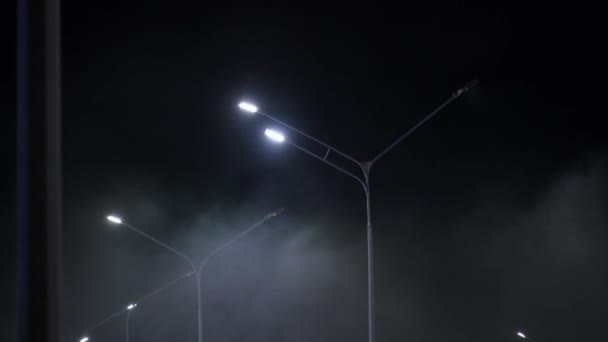 mistige nacht scene in een parkeerplaats met verlichte straatverlichting werpen een gloed door de mist. - Video