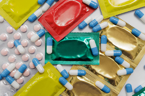 Červené, žluté, zelené kondomy a modré pilulky s kopírovacím prostorem - Fotografie, Obrázek