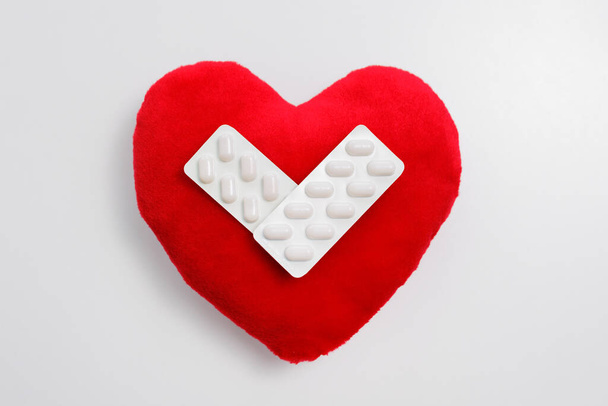 Horní pohled na červený polštář srdce s pilulkami na bílém - Fotografie, Obrázek