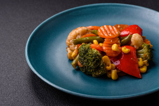 Heerlijke gezonde groenten gestoomde wortelen, broccoli, aspergebonen en paprika 's op een donkere betonnen achtergrond - Foto, afbeelding