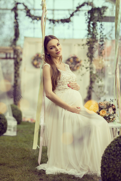 Pregnant woman sitting on swing - Foto, afbeelding