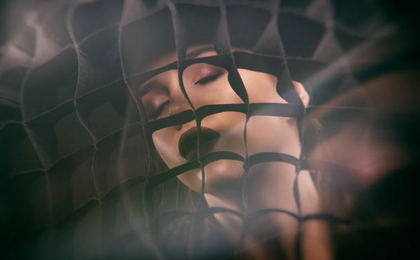Portrait of an attractive brunette with beautiful makeup. She holds a large mesh near her face. - Photo, Image