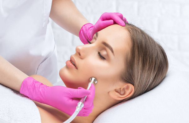 Cosmetologist makes  procedure microdermabrasion on the face against acne and blackheads near the eyes. Women's cosmetology in the beauty salon. - Photo, Image