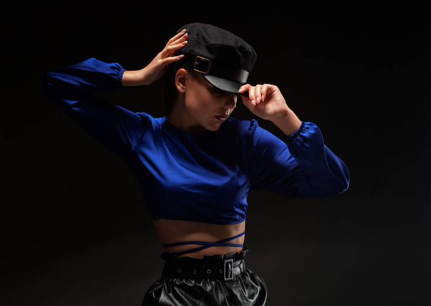 Porträt eines attraktiven Mädchens mit gesunder, sauberer Haut und schönem Make-up. Sie trägt eine blaue Bluse und einen schwarzen Hut. - Foto, Bild