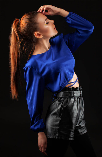 Portrait de fille attrayante avec une peau propre et saine et un beau maquillage. Elle porte un chemisier bleu et une jupe en cuir noir. - Photo, image