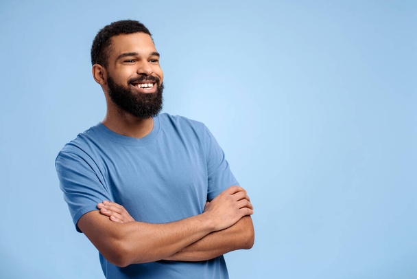 Handsome, authentic African American man wearing casual clothes with crossed arms looking away, copy space, standing isolated on blue background. Concept of advertisement, shopping - Fotografie, Obrázek