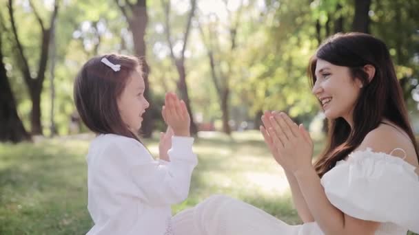 母と娘は公園で手を挙げてゲームをしている. 手のひらを再生, 拍手, 一緒に時間を過ごす - 映像、動画