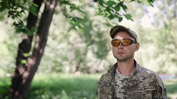 Sotilaspukuinen mies kävelee hidastettuna syvässä metsässä. Asepalveluksen käsite, armeija, velvollisuus. Teksti rinnassa tarkoittaa "Ukrainan Air Assault Forces" ja "Ukraina asevoimat" - Materiaali, video