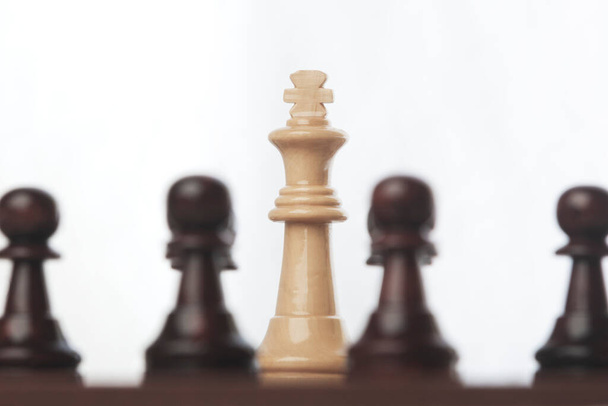 Ο λευκός βασιλιάς σε ένα παιχνίδι σκάκι φαίνεται ανάμεσα στα μαύρα πιόνια. ο λαός εναντίον της εξουσίας.  - Φωτογραφία, εικόνα
