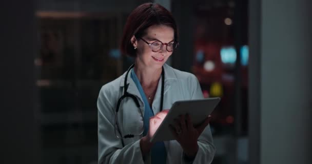 Mature doctor, woman and tablet in night for typing, reading for results, information or research. Medic, happy and digital touchscreen with analysis, telehealth or scroll with smile on app in clinic. - Footage, Video
