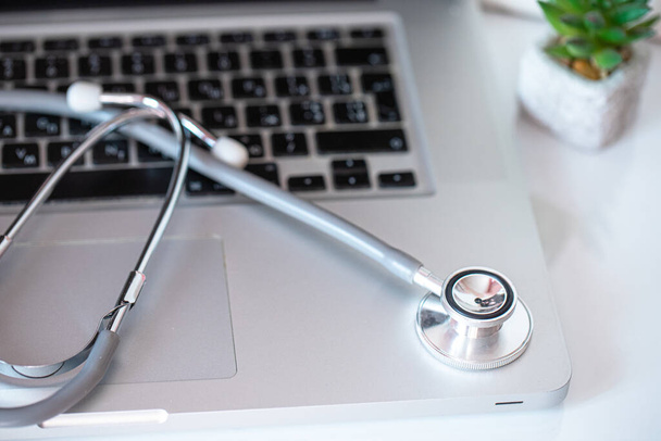 Abordagem inovadora da assistência médica: estetoscópio colocado em um laptop, significando consulta on-line. Conceito de soluções de saúde digital - Foto, Imagem