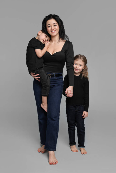 Little children with their mother on grey background - Valokuva, kuva