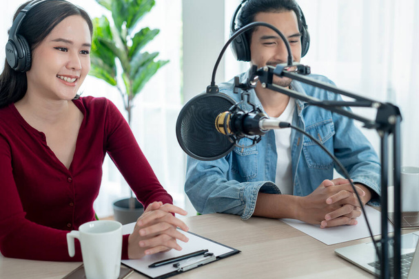 Asiens Männer und Frauen sprechen in einem Radiosender, um Mut zu machen. schöne Frau organisiert das Radioprogramm. Radio, Podcast, Live-Dämpfen, Unterhaltung, Hören, Technologie, Musik - Foto, Bild