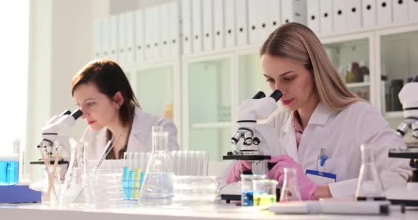 Les femmes scientifiques voient une réaction anormale par microscopes et donnent cinq en laboratoire chimique. Technologues heureux des résultats des tests - Séquence, vidéo