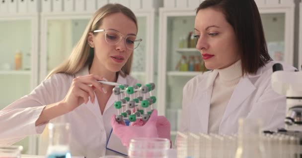 Vrouwelijke wetenschappers onderzoeken de moleculaire structuur in het laboratorium. Onderzoekers analyseren fysisch model ter illustratie van moleculaire structuur slow motion - Video