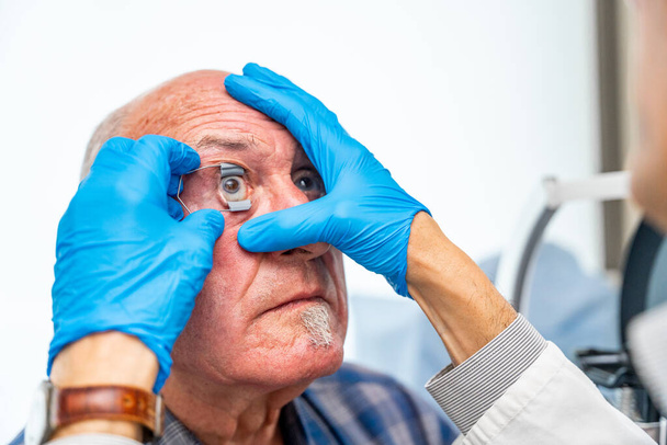 Ophthalmologist applying an eye opener on a senior patient before an innovative treatment for glaucoma - Foto, Imagem