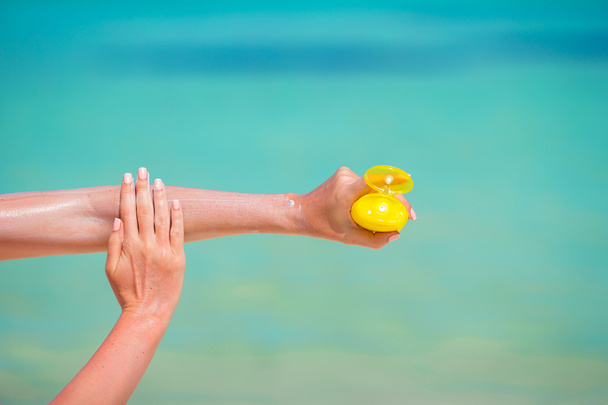 Femme mains mettre crème solaire à partir d'une bouteille de crème solaire - Photo, image
