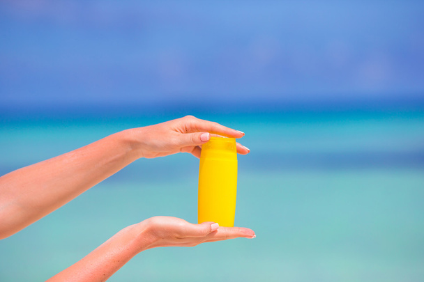Suncream ボトル青背景海で女性の手 - 写真・画像