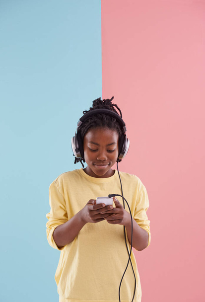 Adolescente, chico y relajarse con teléfono y auriculares en el estudio para escuchar música en la escuela secundaria y la lectura. Feliz, niño y creativo post en las redes sociales con audio y ver transmisión en vivo en la aplicación. - Foto, imagen