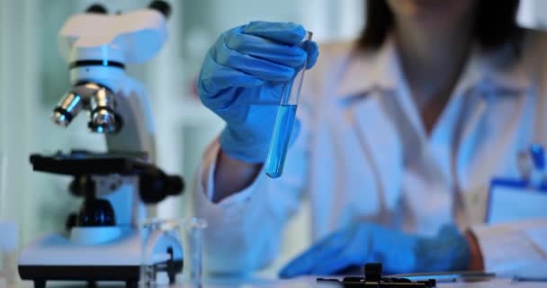Gekwalificeerde wetenschapper onderzoekt kenmerken van blauwe vloeistof in het lab. Onderzoeker onderzoekt chemische eigenschappen van vloeistof in flacon slow motion - Video