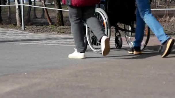 Un sentiero dove la gente cammina, una sedia a rotelle passa, e dopo di esso passa una carrozzina. - Filmati, video