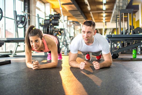 Спортивная пара делает упражнения на доске в спортзале - Фото, изображение