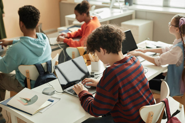 High angle view at teenage schoolboy using laptop in programming class for children - Φωτογραφία, εικόνα