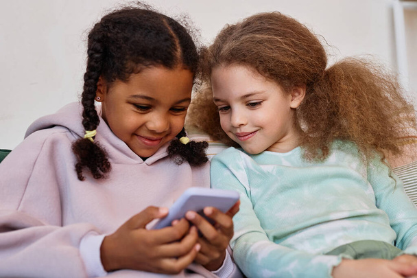 Πορτρέτο των δύο χαριτωμένα μικρά κορίτσια χρησιμοποιώντας smartphone μαζί και παίζοντας παιχνίδια για κινητά - Φωτογραφία, εικόνα