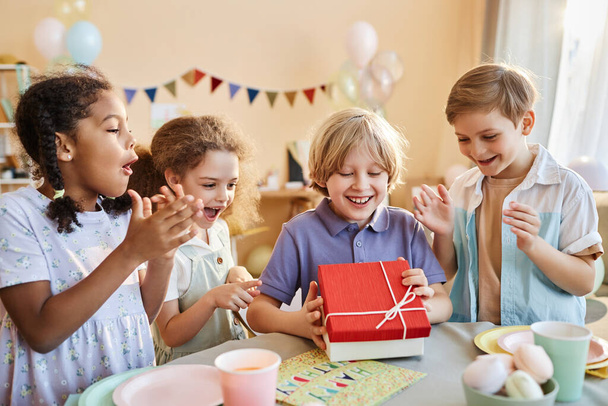 Sokszínű csoport boldog gyerekek születésnapi party izgatott fiú nyitó ajándékok - Fotó, kép