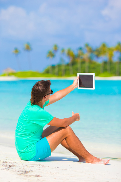 Młody człowiek z laptopa na tropikalnej plaży - Zdjęcie, obraz