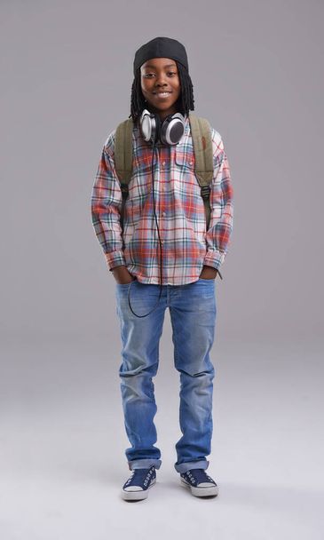 Headphones, happy and portrait of child on gray background for listening to song, audio and radio. Fashion, student and young African boy with bag in trendy style, clothes and outfit in studio. - Photo, Image