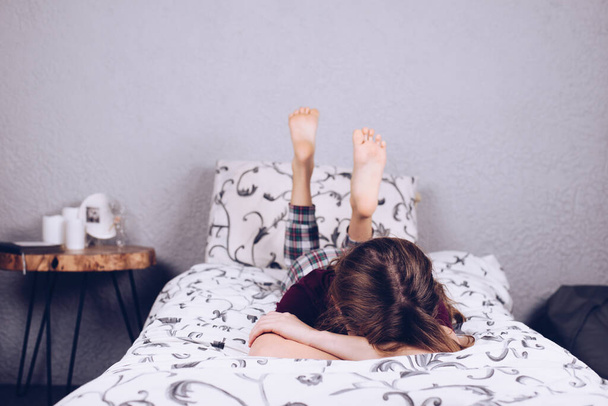 Teinitytön paljain jaloin. Tyttö pyjamassa makaa sängyllä. Jalka ja kantapää - Valokuva, kuva