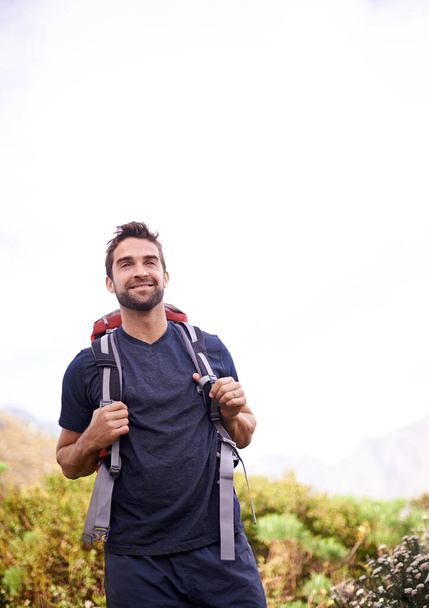 Άνθρωπος, πεζοπορία και χαρούμενος για την περιπέτεια με backpacker για fitness, προπόνηση και χόμπι στην κορυφή του βουνού στην ύπαιθρο. Εξερευνήστε, χαμόγελο και υπαίθρια δραστηριότητα στη φύση για υγιή μυαλό σε δάση στις διακοπές. - Φωτογραφία, εικόνα