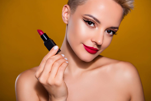 Foto von Frau halten roten Lippenstift Pomade isoliert gelben Senf Farbe Hintergrund. - Foto, Bild