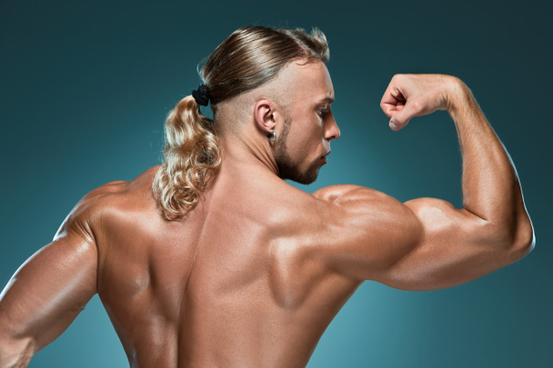 Attractive male body builder on blue background - 写真・画像