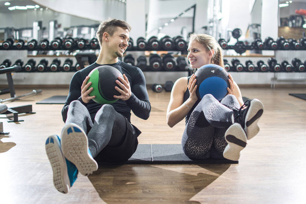 Κατάλληλο ζευγάρι κάνει κοιλιακή άσκηση με μπάλες γυμναστικής στο γυμναστήριο - Φωτογραφία, εικόνα