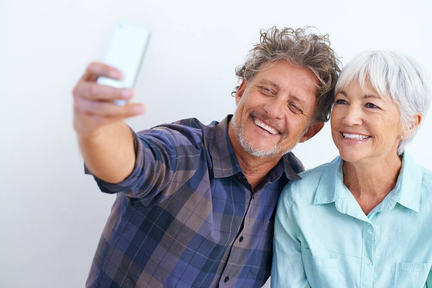 Altes Paar, Selfie und glücklich zusammen für Social-Media-Post, Erinnerung und Liebe mit Freude auf weißem Hintergrund. Vertrauen, Unterstützung und Loyalität mit Menschen in der Ehe, Lächeln im Bild für Post und mobile App. - Foto, Bild