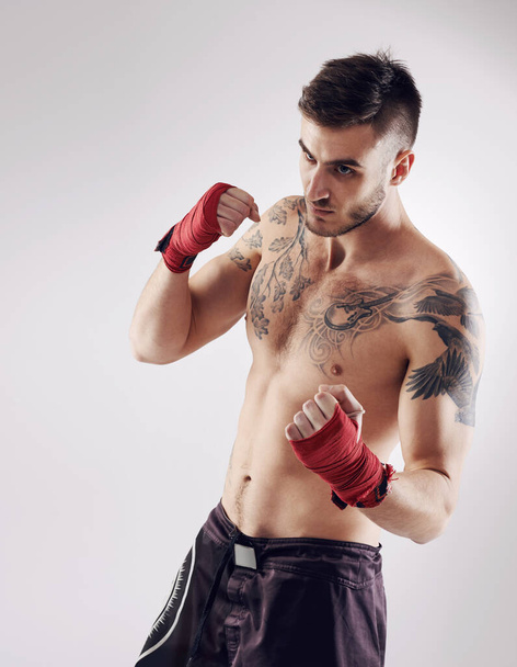 Ököl, MMA és csomagok férfi harcos vagy bokszoló, pózol és boksz fehér háttérrel. Fitness, kéz és sportoló a testmozgás és férfi kickboxer, stúdió vagy képzés ütközés sport vagy verseny. - Fotó, kép