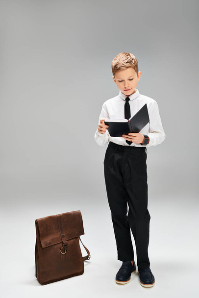 Mladý chlapec v elegantním oblečení stojící vedle kufříku. - Fotografie, Obrázek