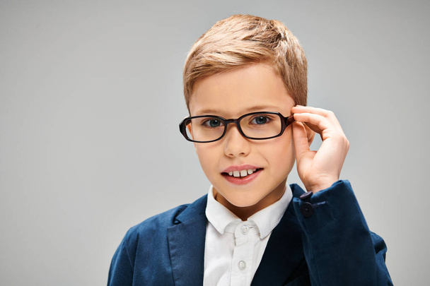 Un piccolo ragazzo preadolescente in occhiali e un vestito, trasudante intelligenza ed eleganza. - Foto, immagini