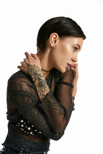 Een jonge vrouw met een opvallende tatoeage siert haar arm en staat in een studio met haar partner tegen een grijze achtergrond. - Foto, afbeelding