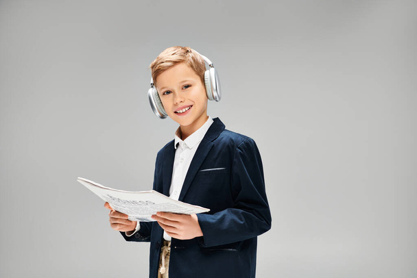 Giovane ragazzo in elegante abbigliamento indossando cuffie, in possesso di carta. - Foto, immagini