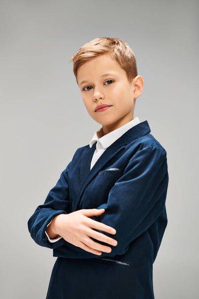 Εφηβικό αγόρι σε κομψό μπλε κοστούμι στέκεται με σταυρωμένα τα χέρια. - Φωτογραφία, εικόνα
