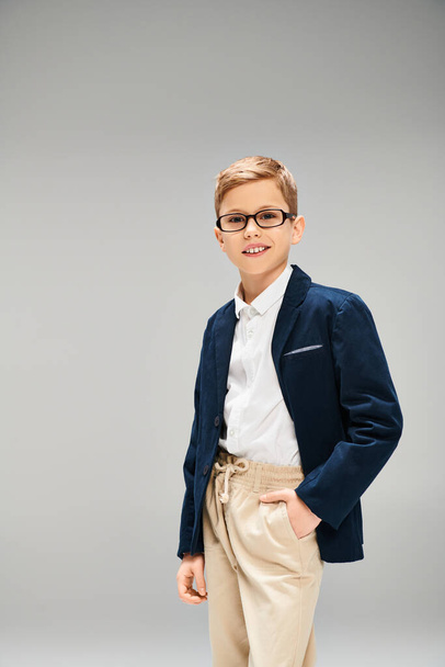 Предприимчивый мальчик в стильном костюме и очках, излучающий уверенность и уверенность. - Фото, изображение