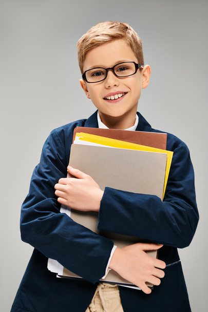 Ένα αγόρι με κοστούμι και γυαλιά που κρατάει ένα φάκελο.. - Φωτογραφία, εικόνα
