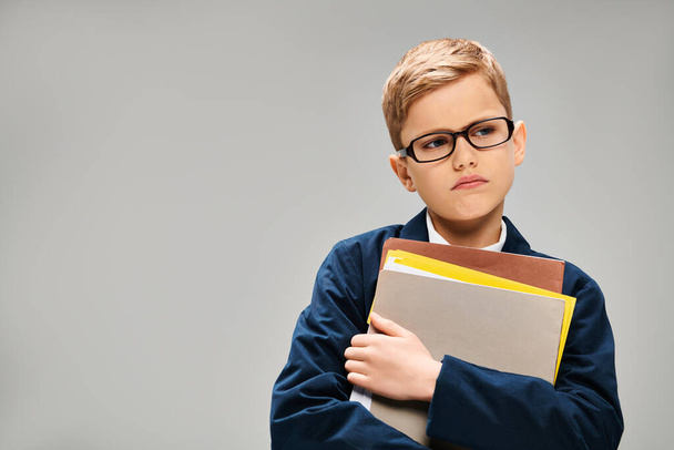 Kleiner Junge mit Brille hält einen Ordner in der Hand, der Intellekt und Ehrgeiz ausstrahlt. - Foto, Bild