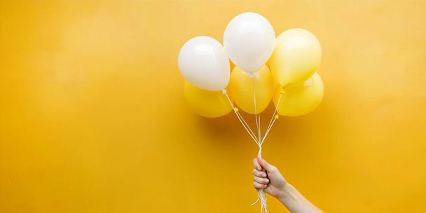 プロダクト割引昇進の考えが付いている抽象的な背景. 黄色のバックグラウンドで白と黄色の気球を保持する女性の手. バナー,コピースペース,ウェブサイト,インスピレーション,思考. - 写真・画像