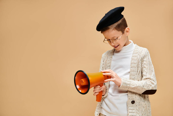 A young boy dressed as a film director confidently holding a yellow and black megaphone. - Photo, Image