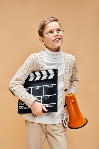 Předdospívající chlapec oblečený jako filmový režisér drží film tleskat. - Fotografie, Obrázek